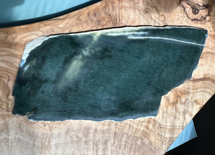Wyoming Slab 230g dark blue-green slab with pale edge on a wood grain background
