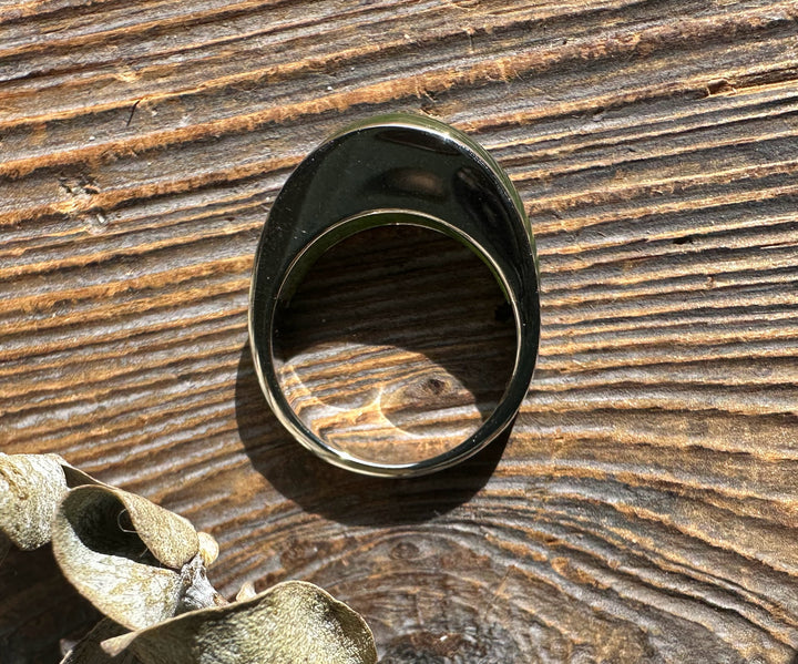Top view of Canadian Jade Ring 3399 showcasing the green jade cabochon in a silver bezel on textured wood