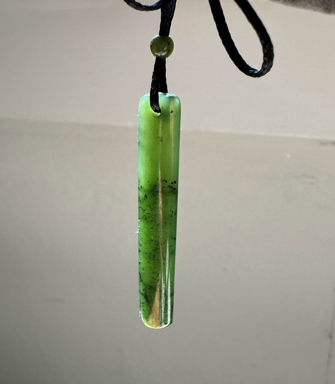 Lime green jade drop pendant on a black cord with a small round bead