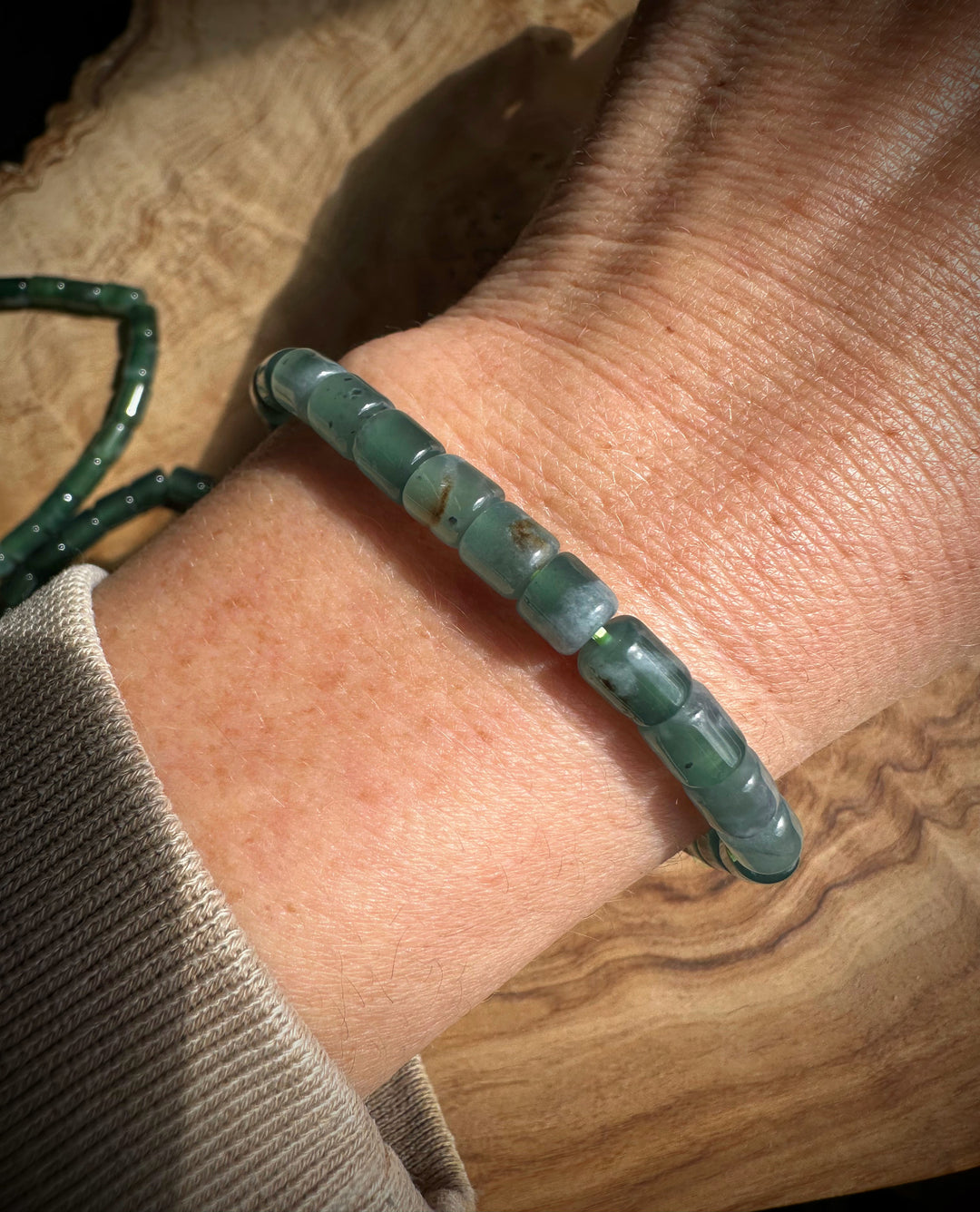 Green beaded bracelet on a wrist with a wooden surface background