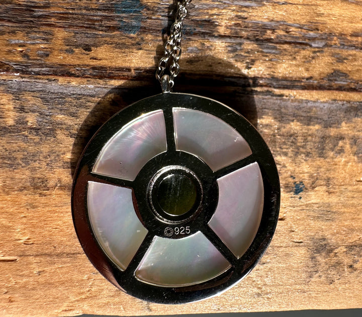 Back view of round pendant showing four segment panels of mother of pearl around a central green stone with a 925 stamp