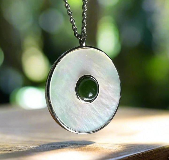 Round pendant featuring a green jade center embedded in a mother of pearl disc on a silver chain