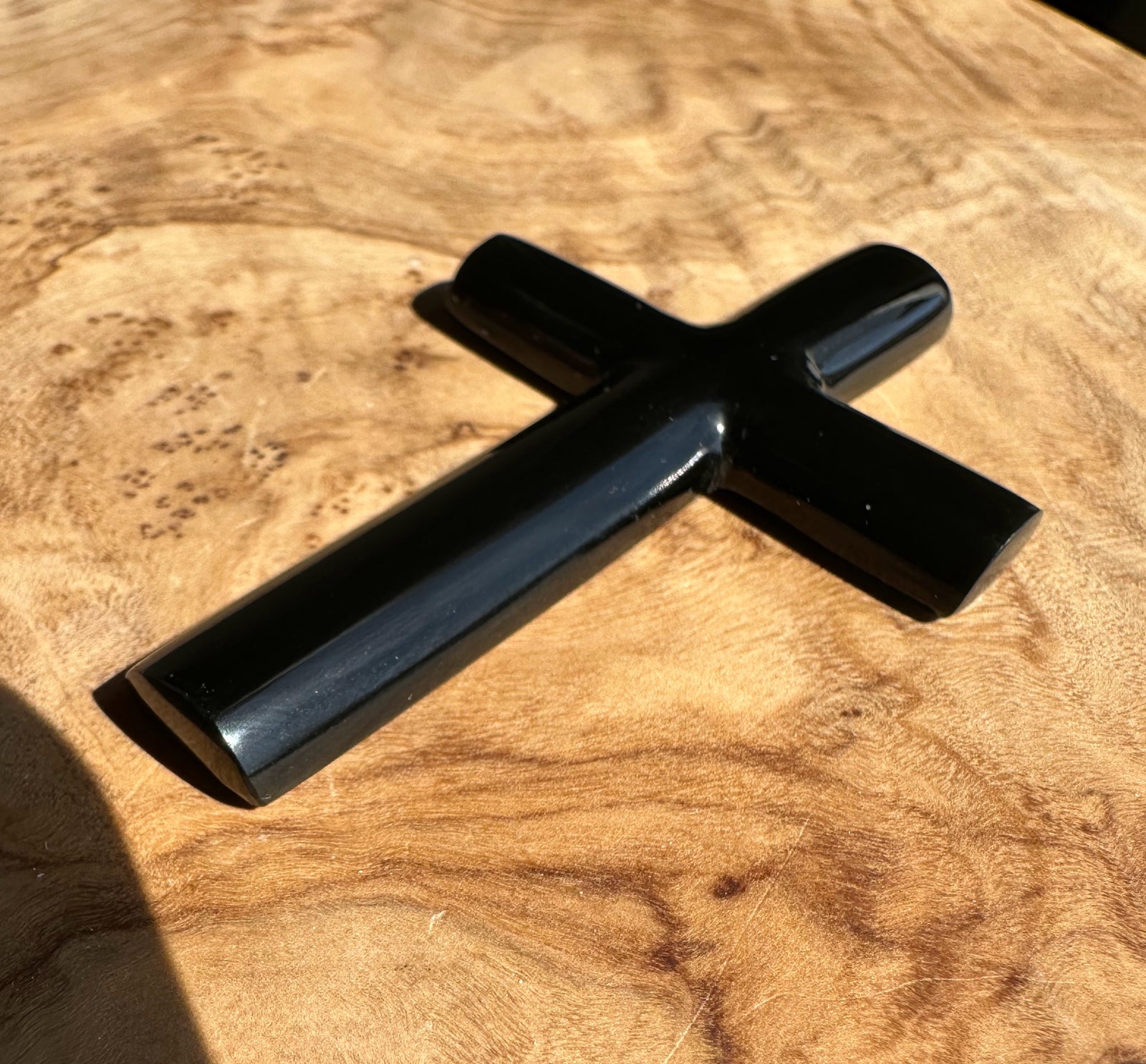 Black jade cross on a wooden surface