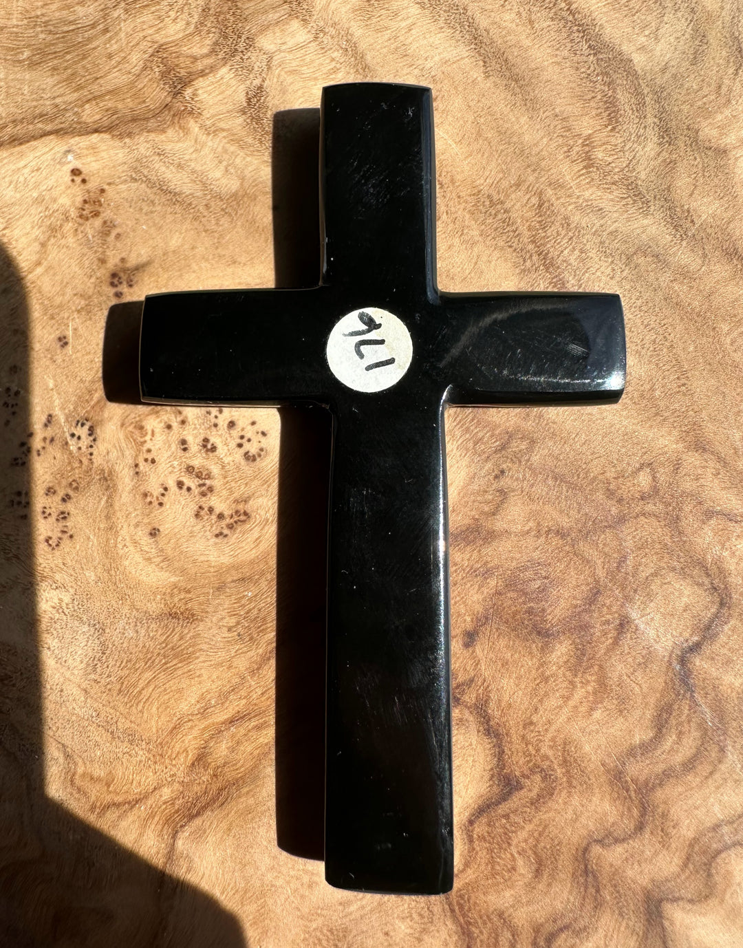 Black cross with a white removable sticker and on a wooden surface
