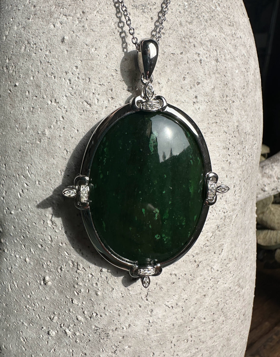 Canadian Jade and Zircon Pendant on a silver chain against a textured stone background