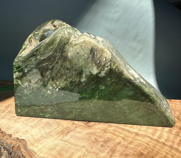 Side view of green jade candle holder showing a circular hollow and natural veining pattern.