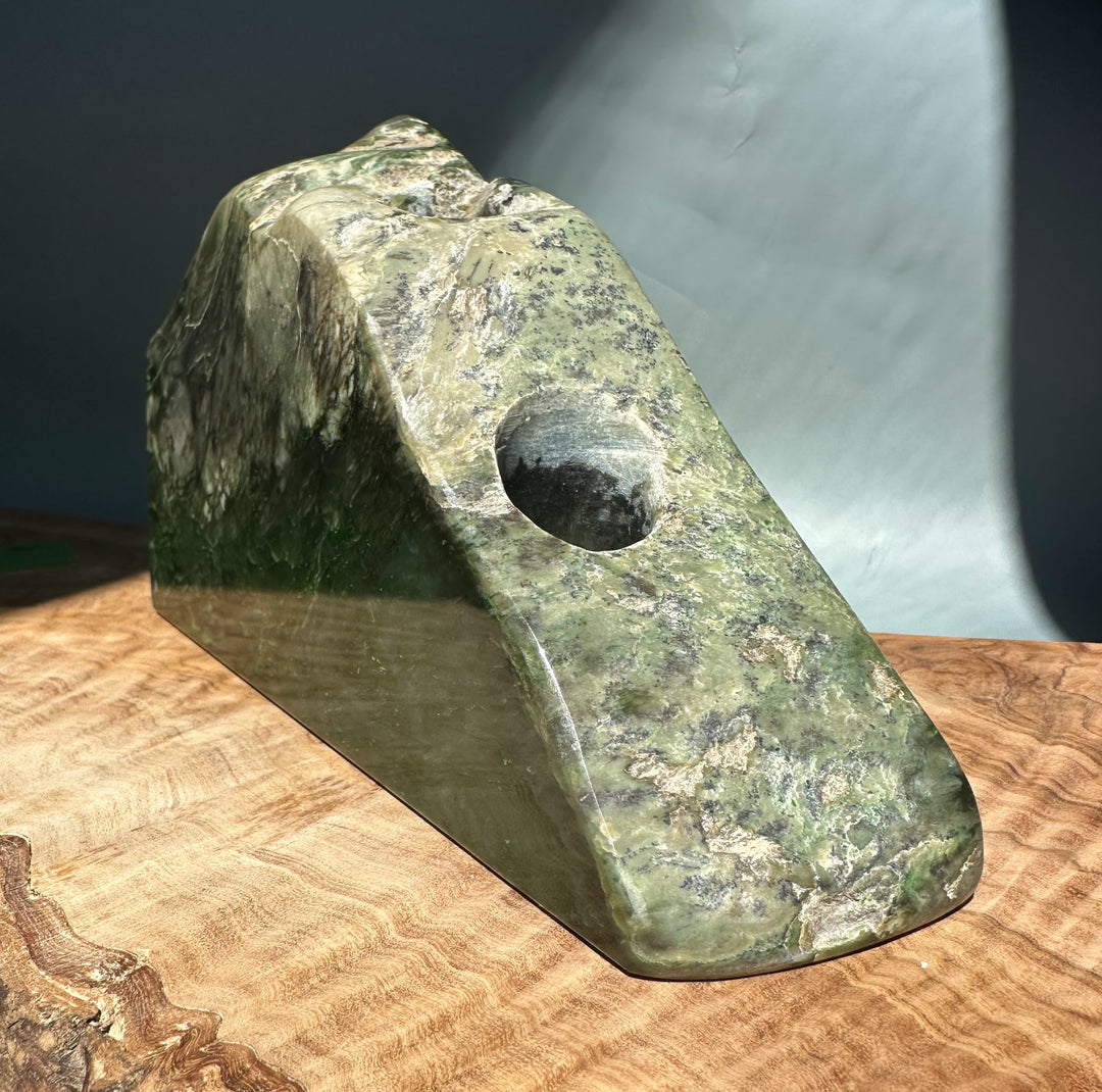 Angled view of jade candle holder with a circular cutout and rich green marbling.