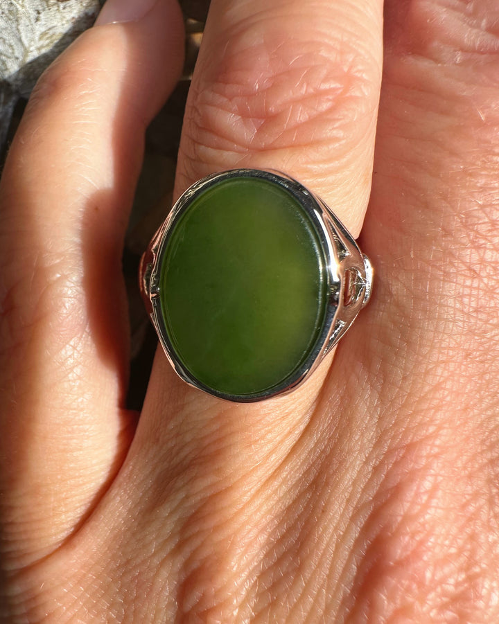 Close-up of the ring worn on a finger showing the green jade centerpiece and ornate silver setting
