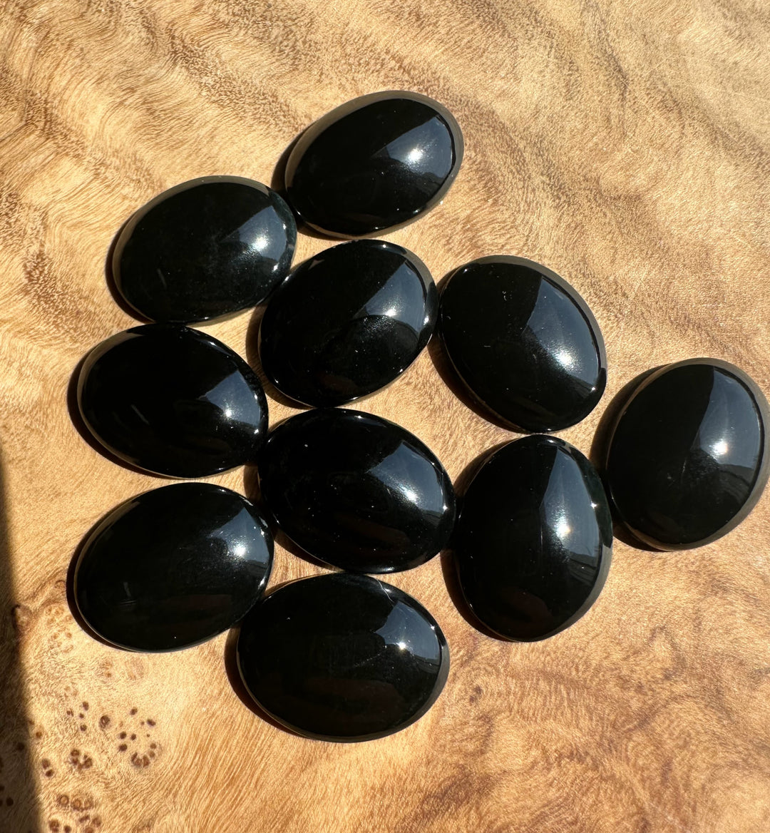 Black jade oval stones on a brown surface