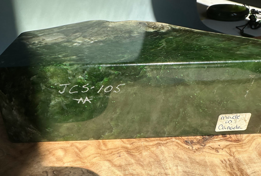 Dark green jade candle holder with a rough natural top, smooth sides, JCS 105 inscription on the side and a made in Canada sticker
