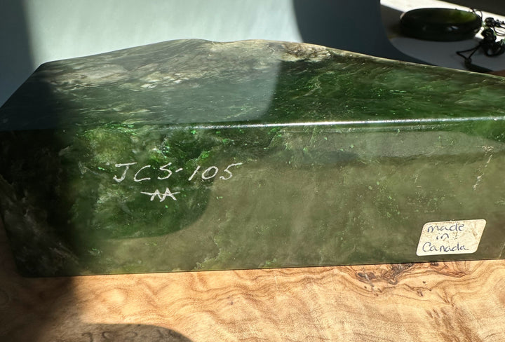 Dark green jade candle holder with a rough natural top, smooth sides, JCS 105 inscription on the side and a made in Canada sticker