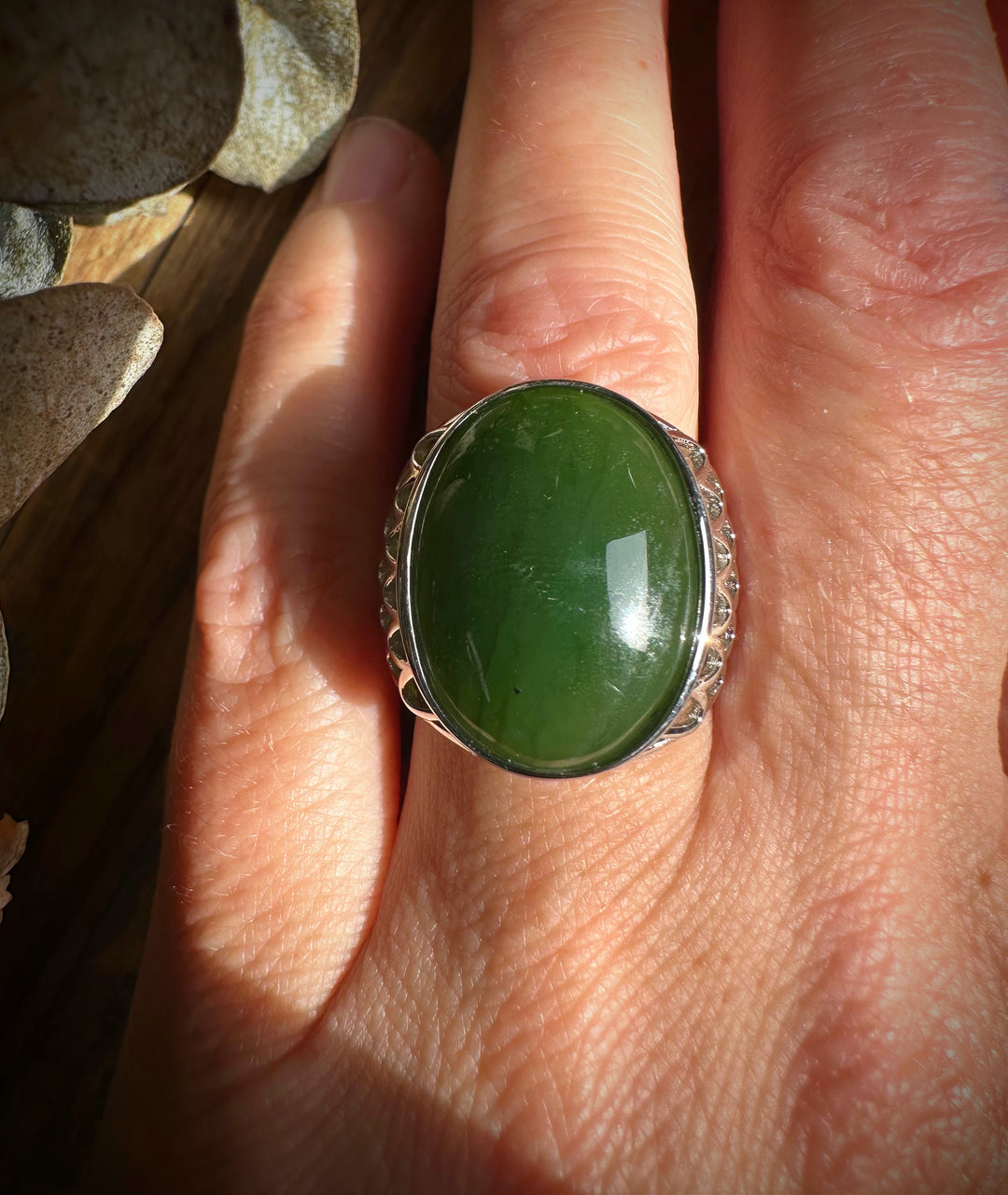 Worn view of Canadian Jade Ring 2570 with an oval green jade cabochon in a silver lattice setting on the finger.