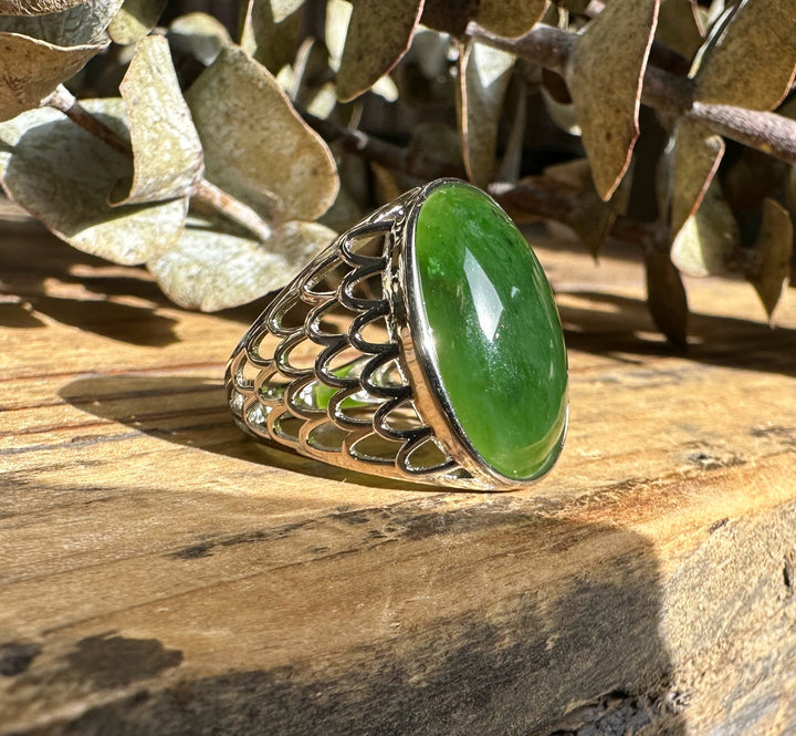 Canadian Jade Ring shown from a side angle with oval green jade cabochon and a detailed openwork silver band