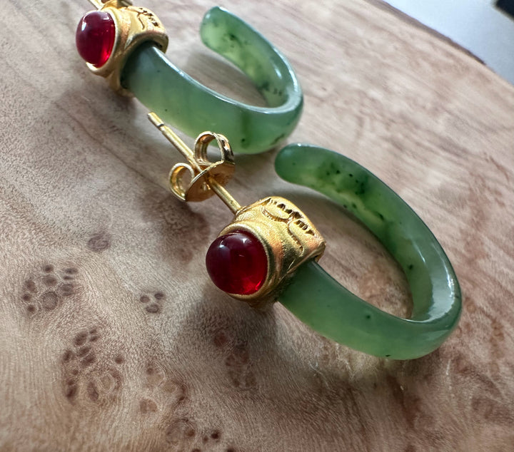 Green jade bracelet with a gold ring set with a red cabochon on a suede surface