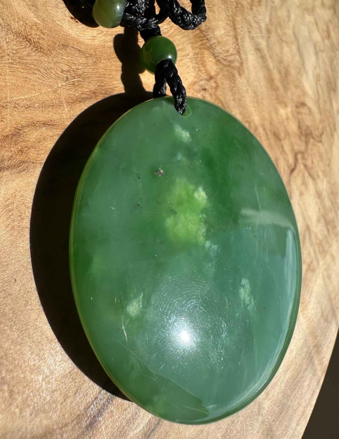 Green jade pendant on a wooden surface