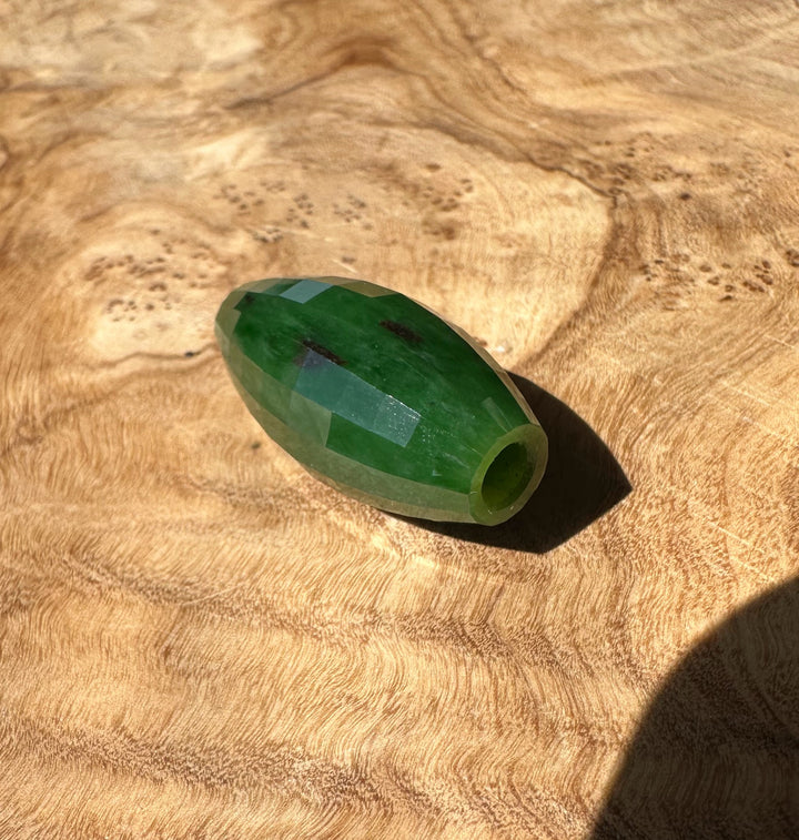 Green jade bead on a wooden surface