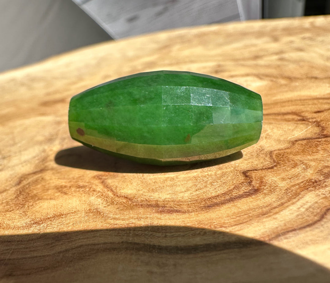 Green faceted jade on a wooden surface