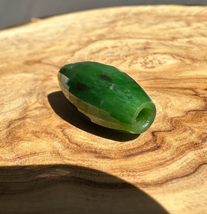 Green jade bead on a wooden surface