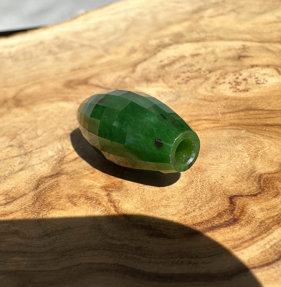 Green faceted bead on a wooden surface