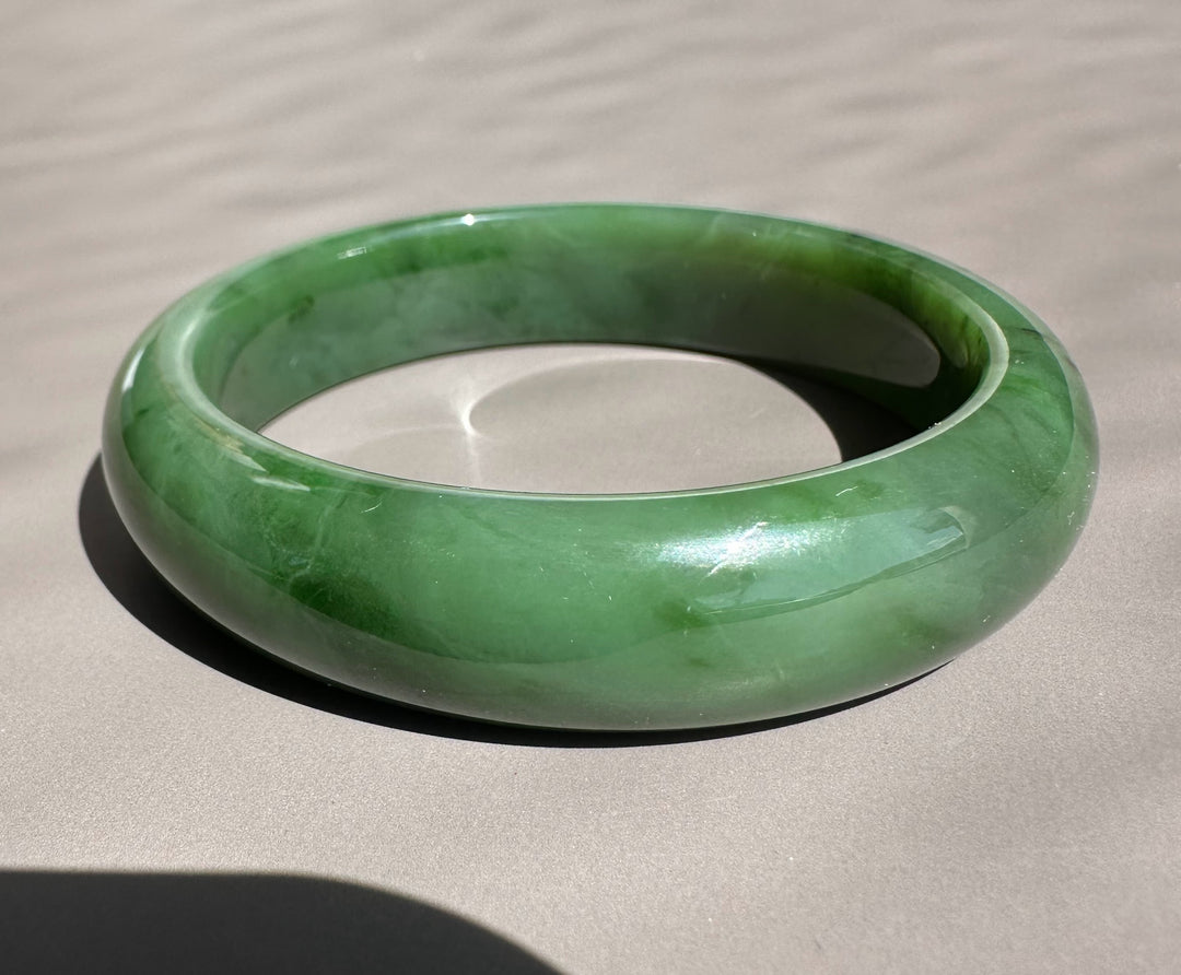 Canadian Jade Bangle in vivid green with a glossy finish and thick circular form on a light surface