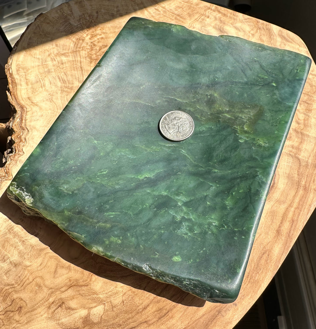 Green stone with a coin on top, placed on a wooden surface