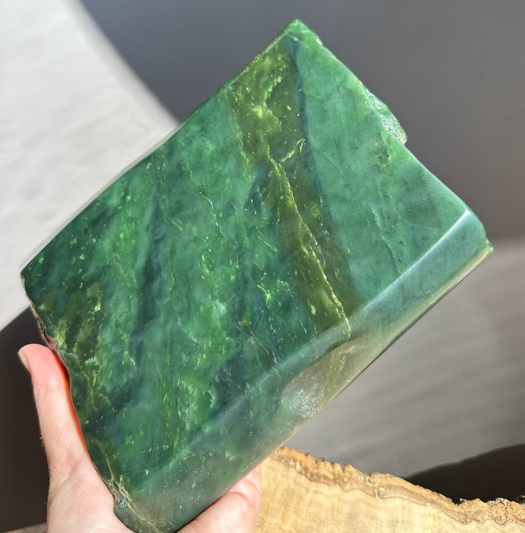 Green stone held in a hand with a blurred background