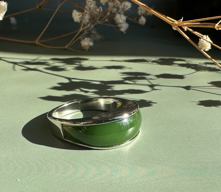 Canadian Jade Ring 3399 close up showing green jade inlay set in a silver band on a green surface