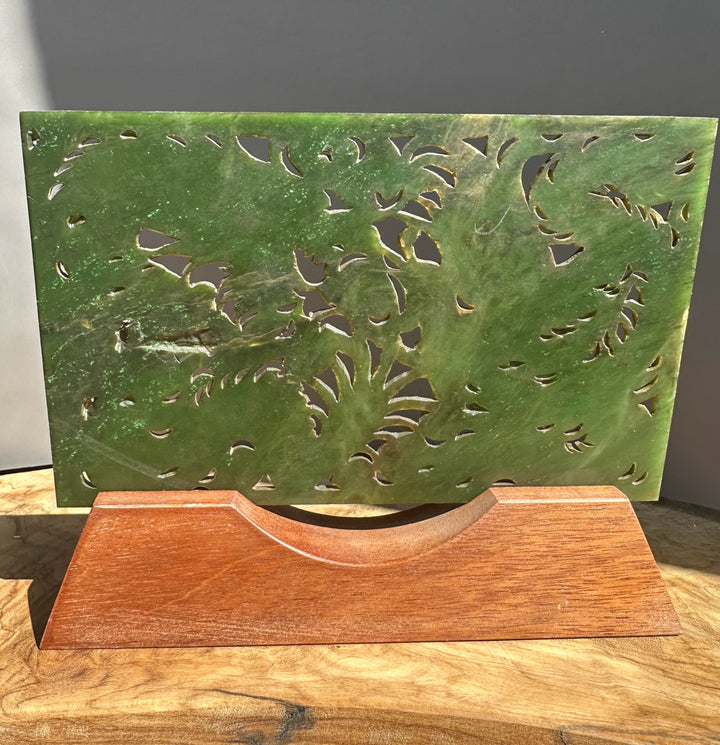 Green decorative panel with cut-out patterns on a wooden surface