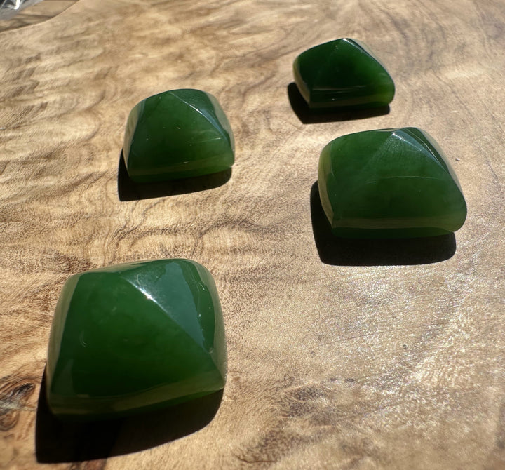 Four green stones on a wooden surface