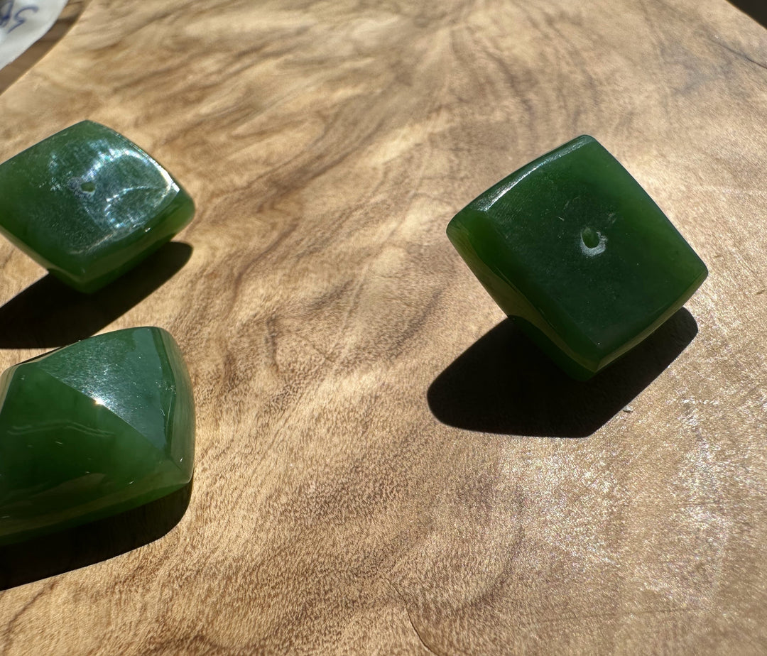 Three green jade stones on a wooden surface