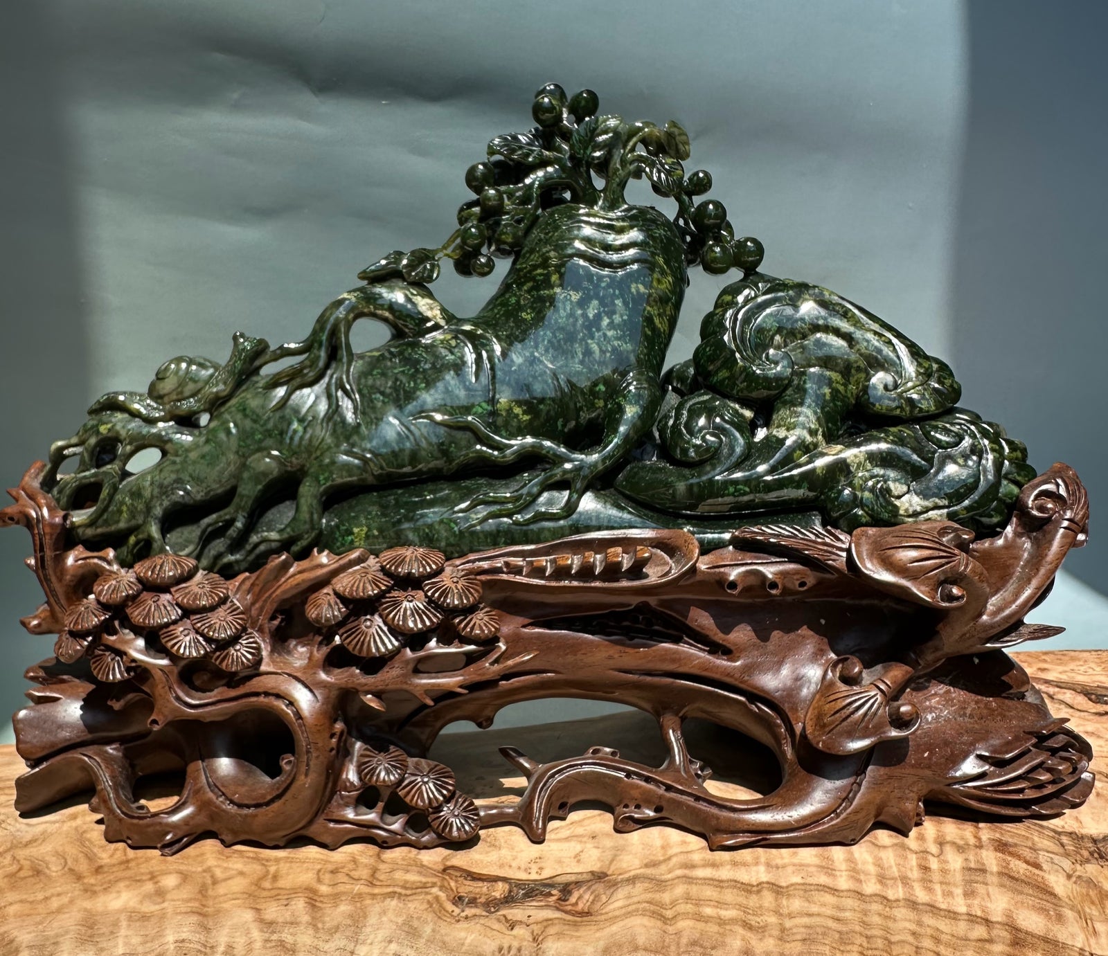 Unique Canadian Cassiar sculpture featuring a green jade mountain and tree motif atop an ornate carved wooden base with mushroom details