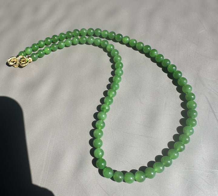 Green beaded necklace on a light gray background