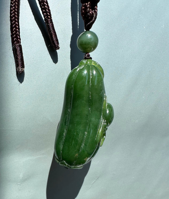 Green Canadian jade spider and gourd pendant on a dark braided cord with a round bead above the gourd