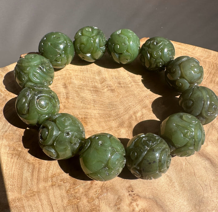 Green jade bracelet with carvings on a wooden surface