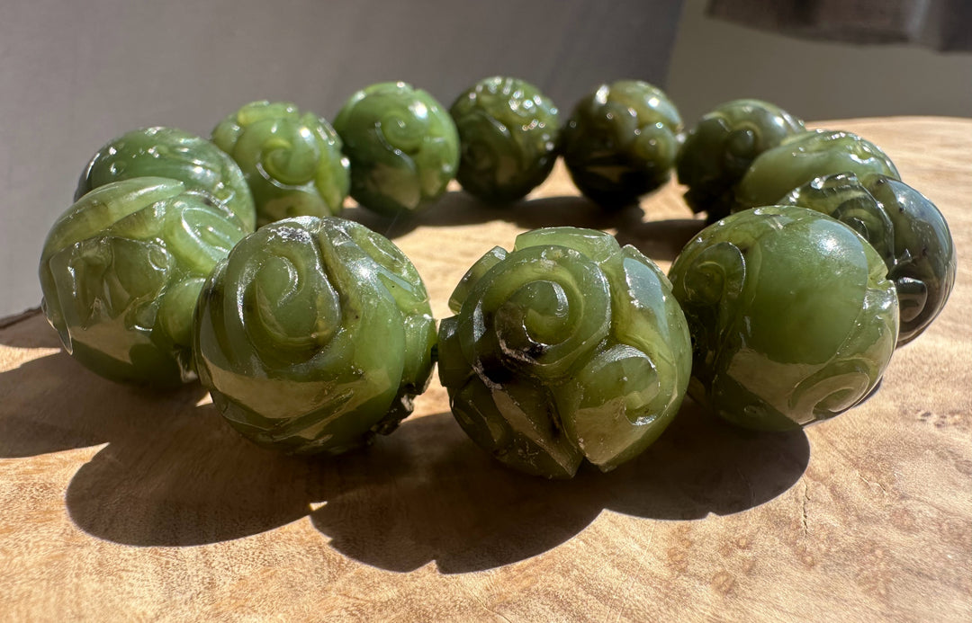Green jade bracelet with floral designs on a wooden surface