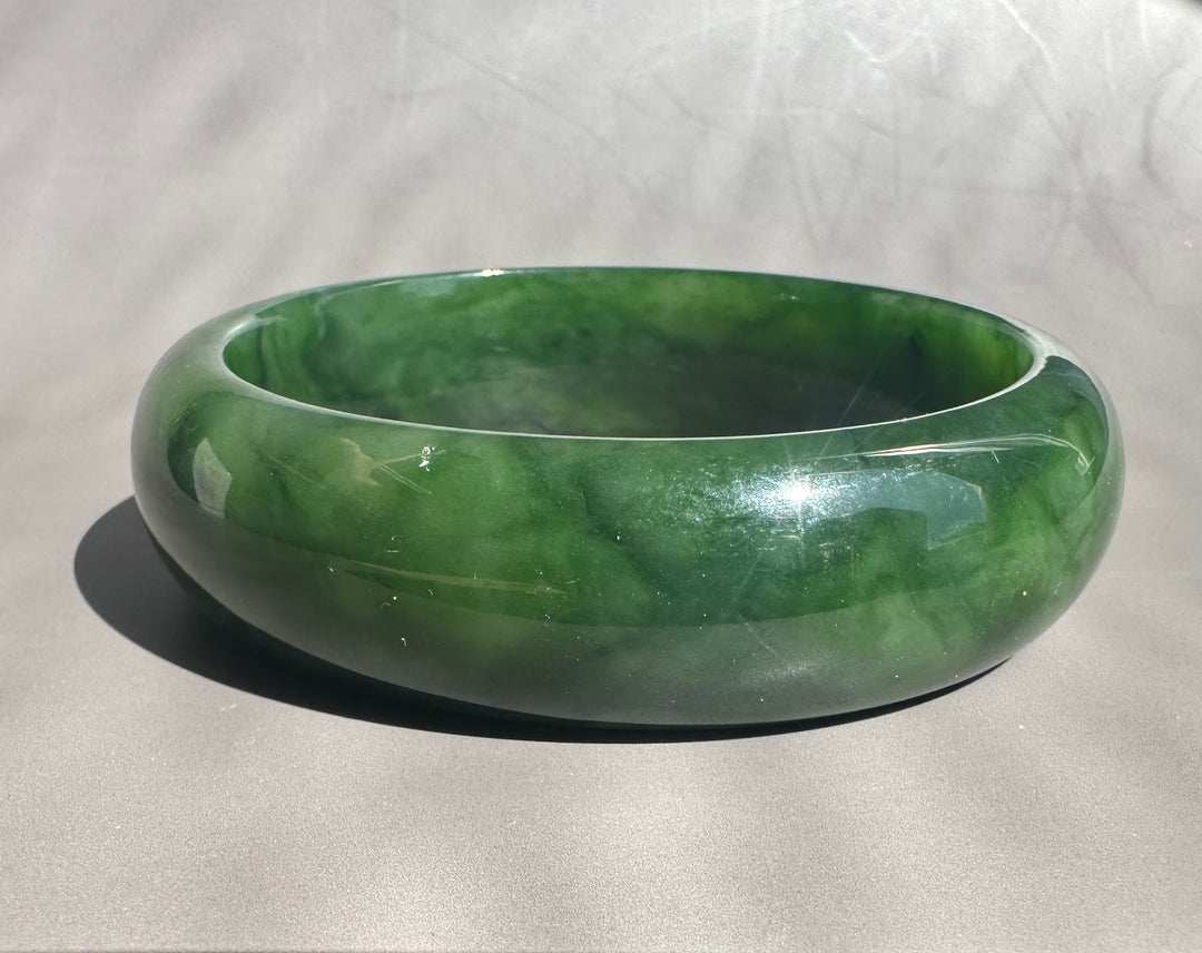Green jade bangle on a light gray background