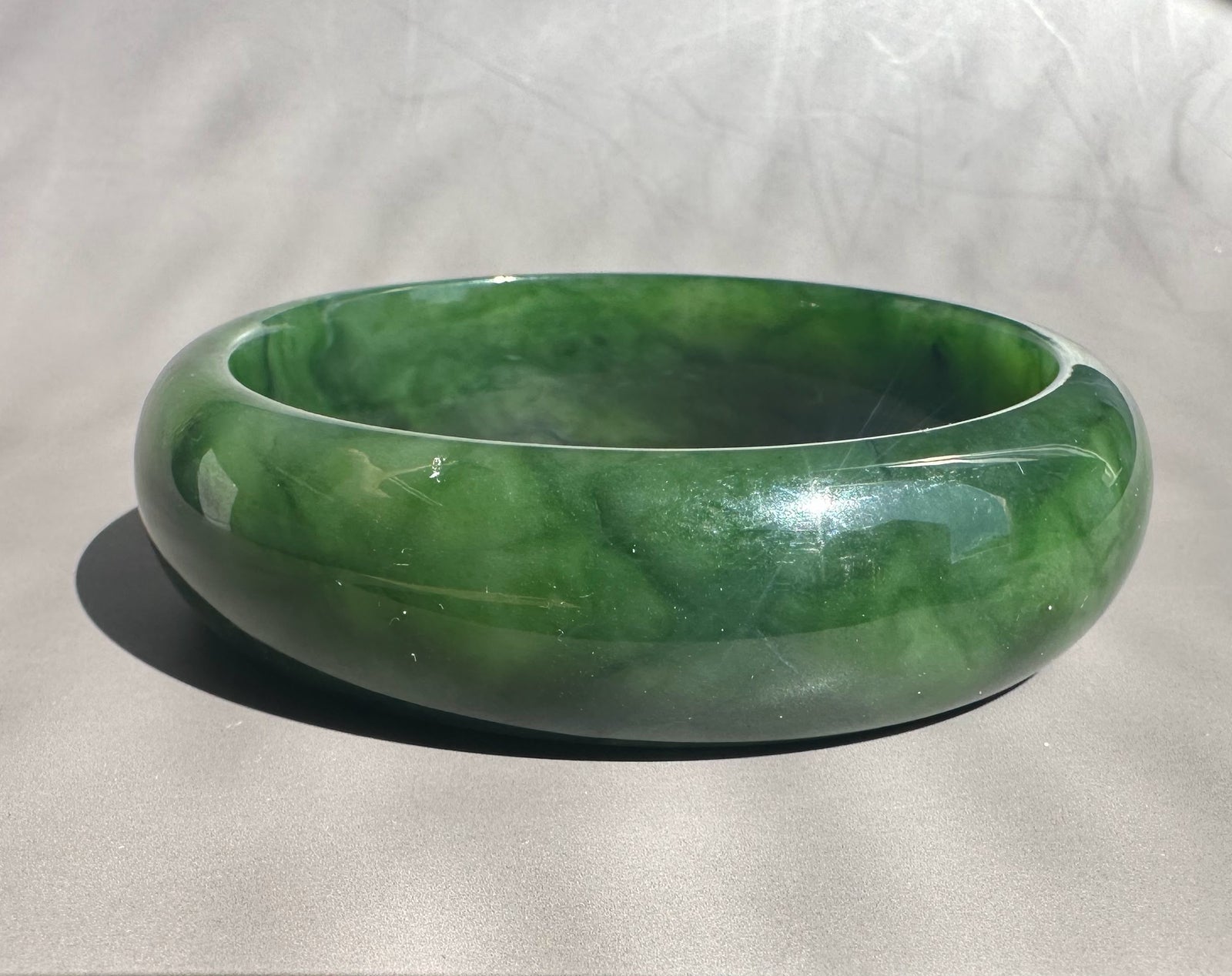 Green jade bangle on a light gray background
