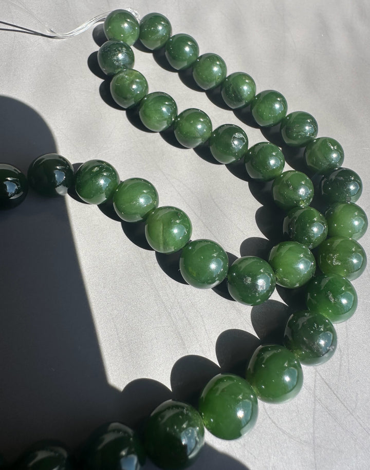 Green beaded necklace on a light gray background