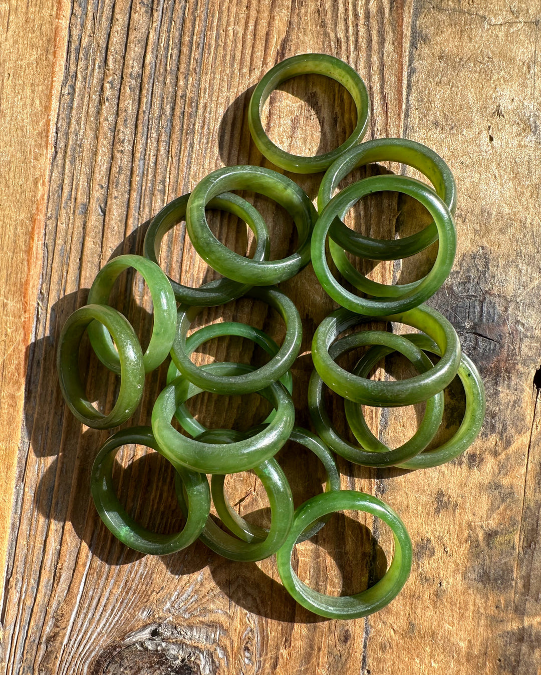 Pile of green jade bangles on a weathered wooden surface