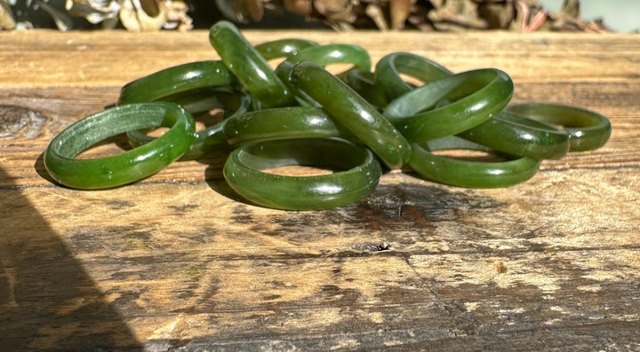 Several green jade bangles stacked and scattered on a rustic wooden surface