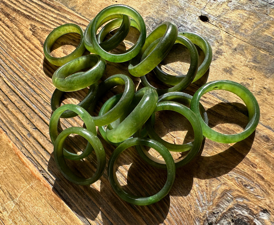 A pile of green jade band rings on a rustic wooden surface