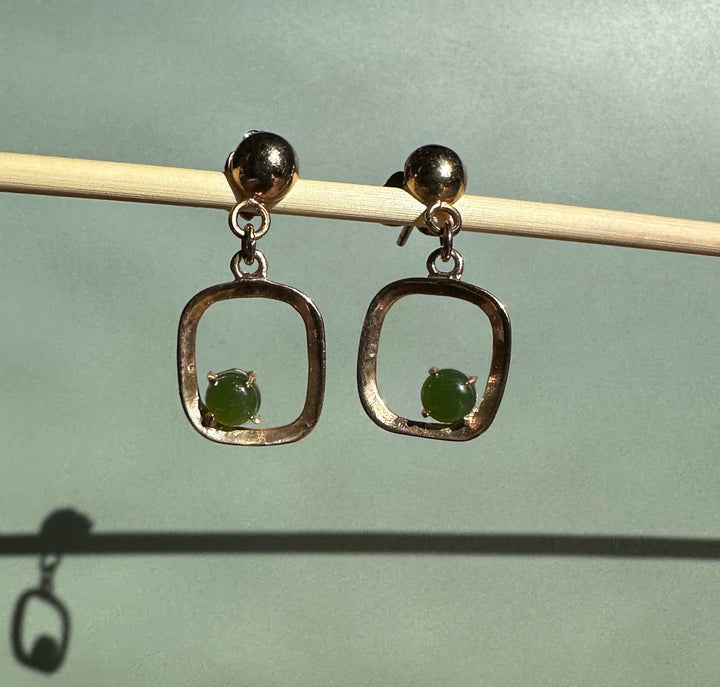 Close-up of vintage jade earrings showing square open frames and green beads