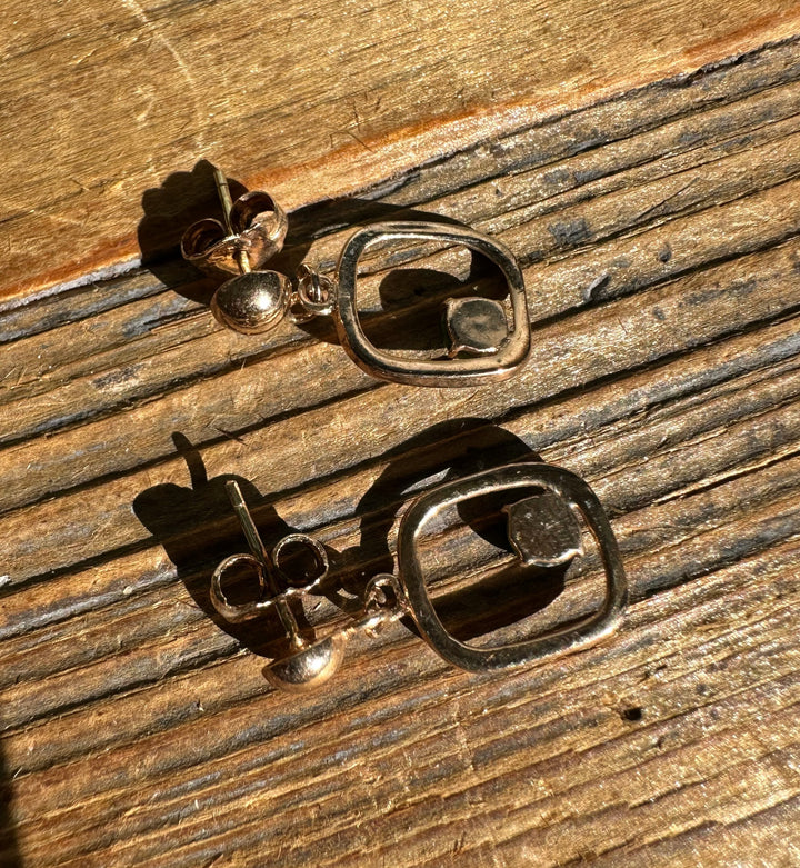 Disassembled Vintage Jade Earrings with open square frames and green stones on a wooden surface