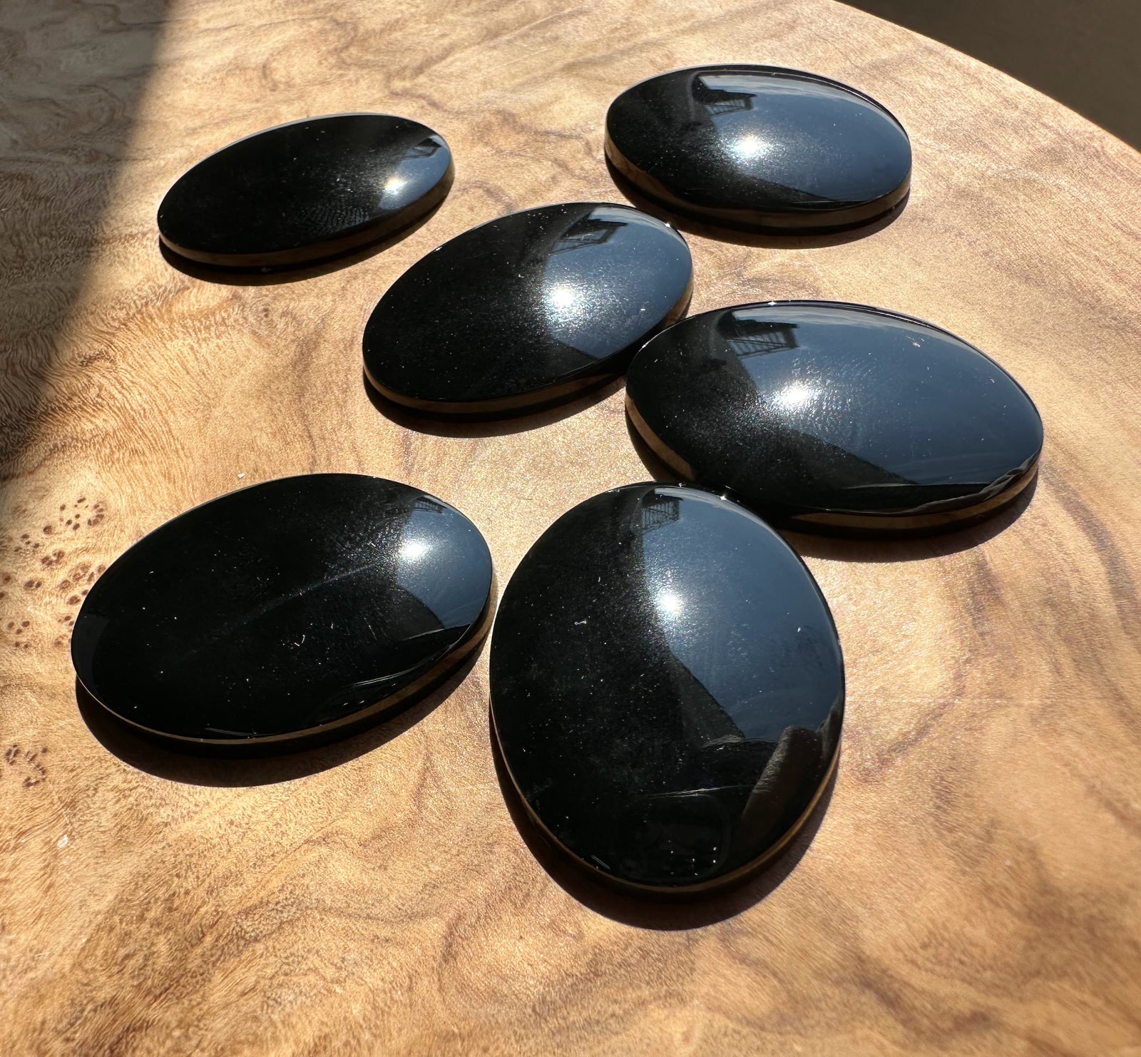 Oval black jade cabochons polished and arranged on a wooden surface