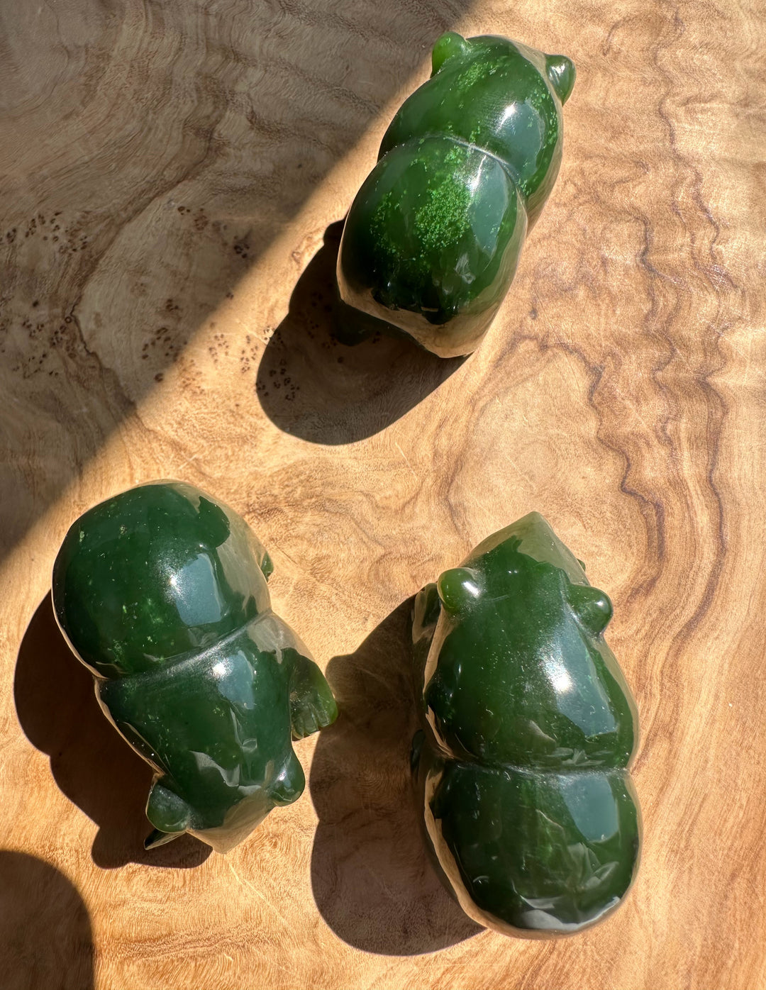 Multiple green jade bear figurines arranged on a wooden surface