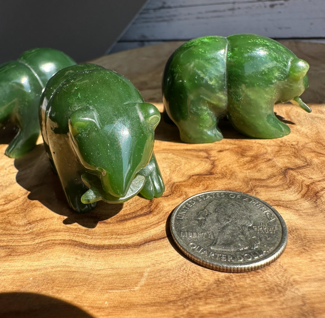Close up of a glossy green jade bear with a coin for scale