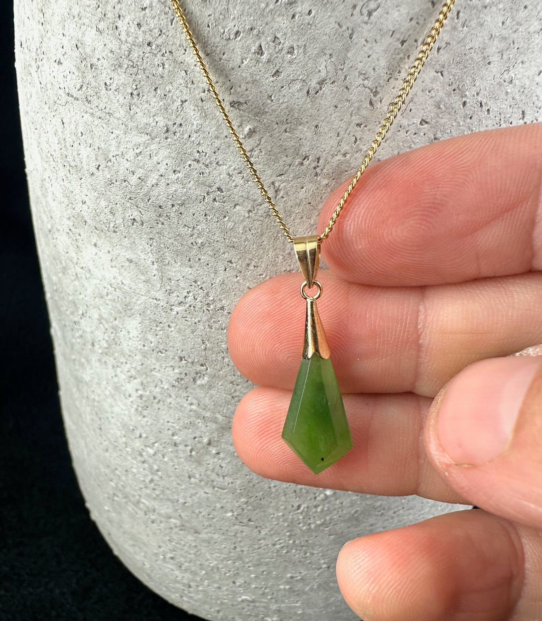 Close-up of a vintage drop pendant featuring a green teardrop gemstone on a gold chain