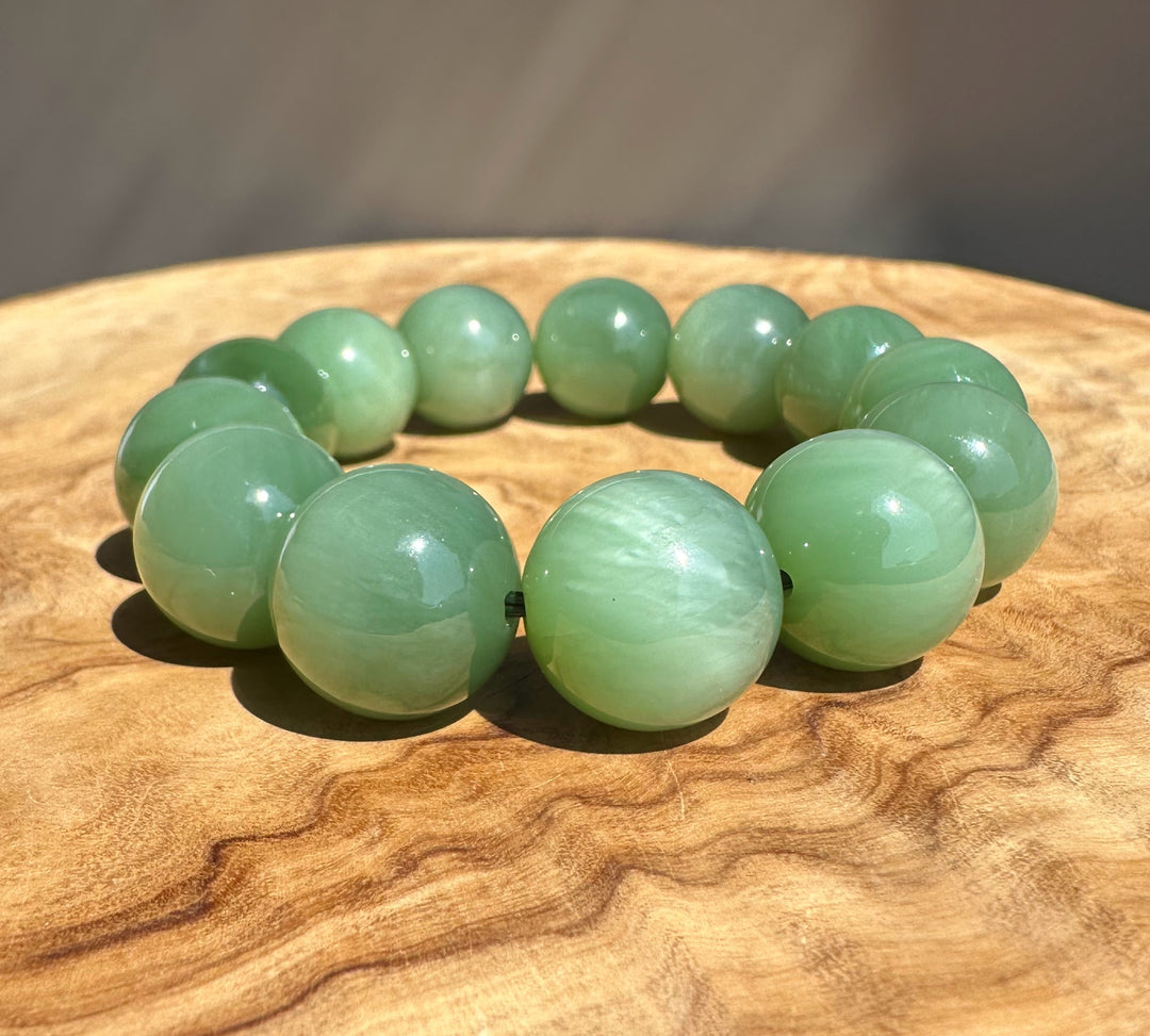 chatoyant jade beads on wooden base