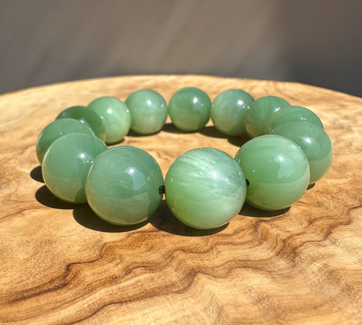 chatoyant jade beads on wooden base