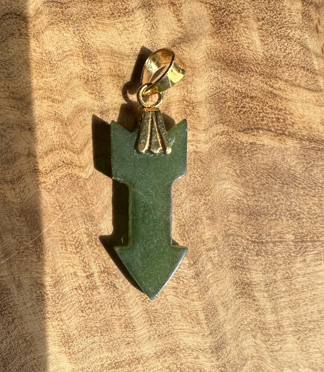 Green jade arrow on wooden base